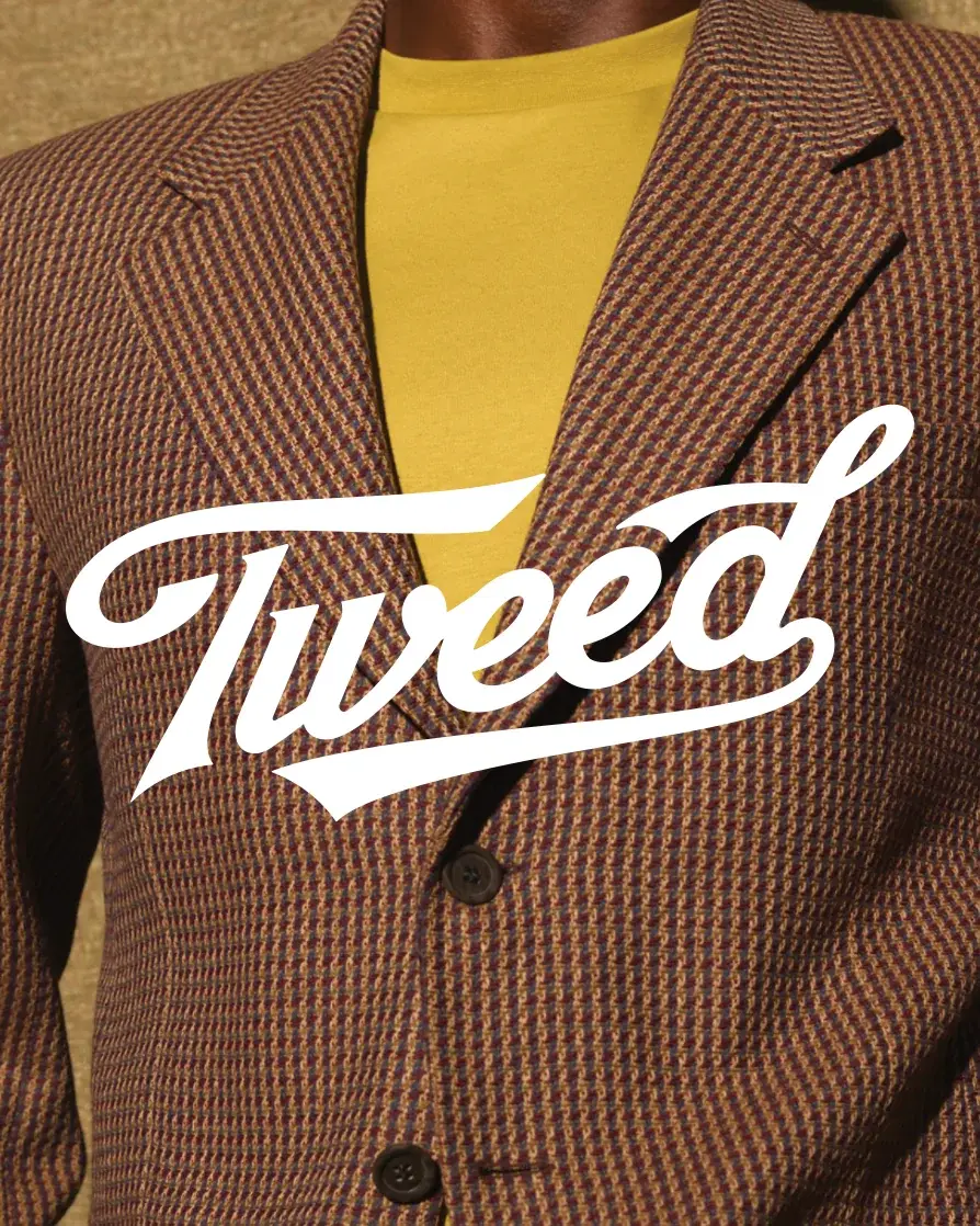 The Tweed script wordmark in white, set over a close-up of a brown tweed jacket worn with a mustard tee.