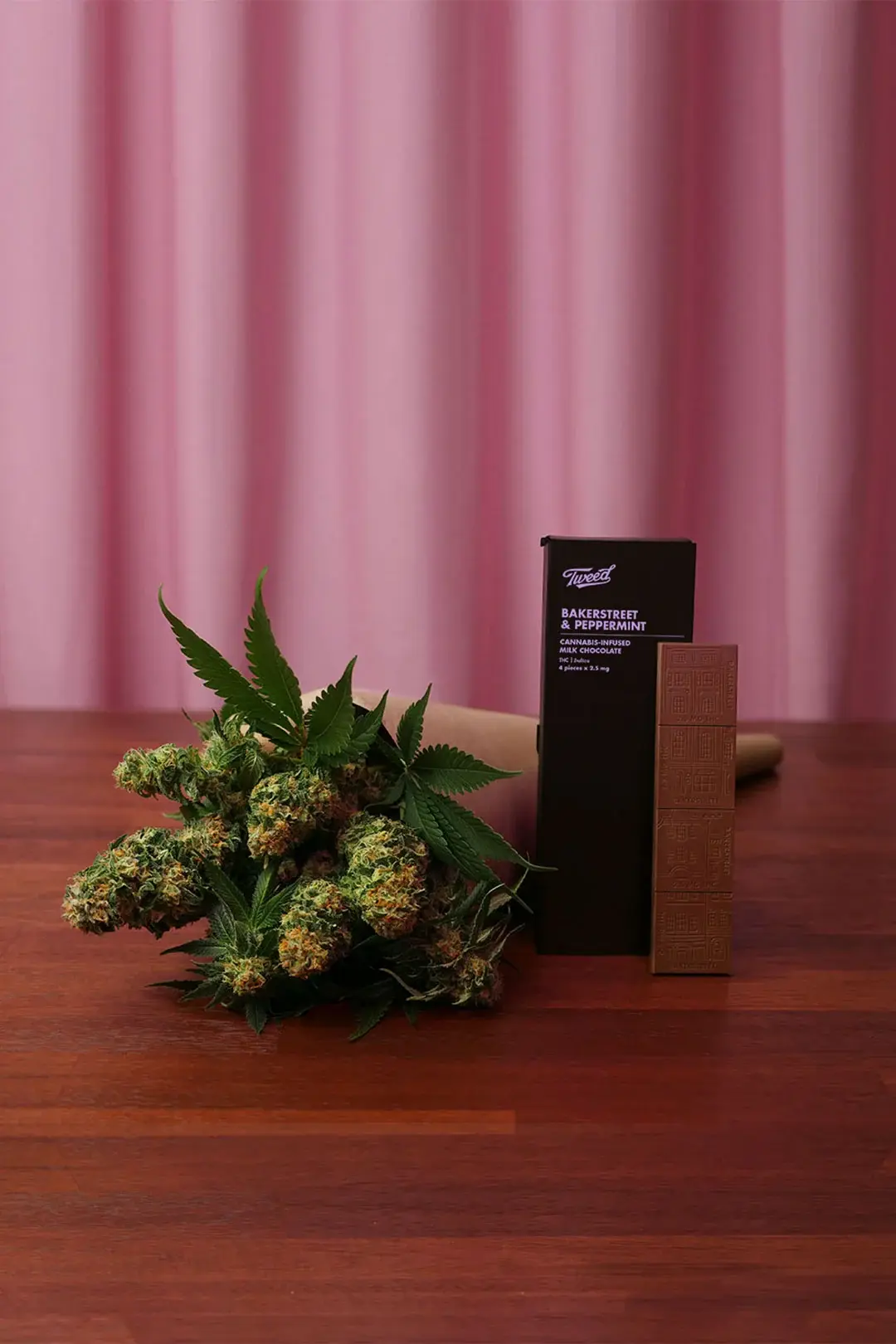 The pairing shot: the bud bouquet beside the chocolate carton, lit against the pink curtain.